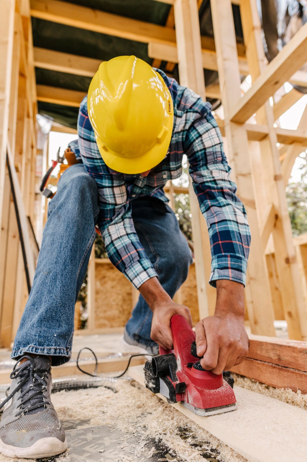 construction-worker-with-hard-hat-sanding-down-wood-piece-min